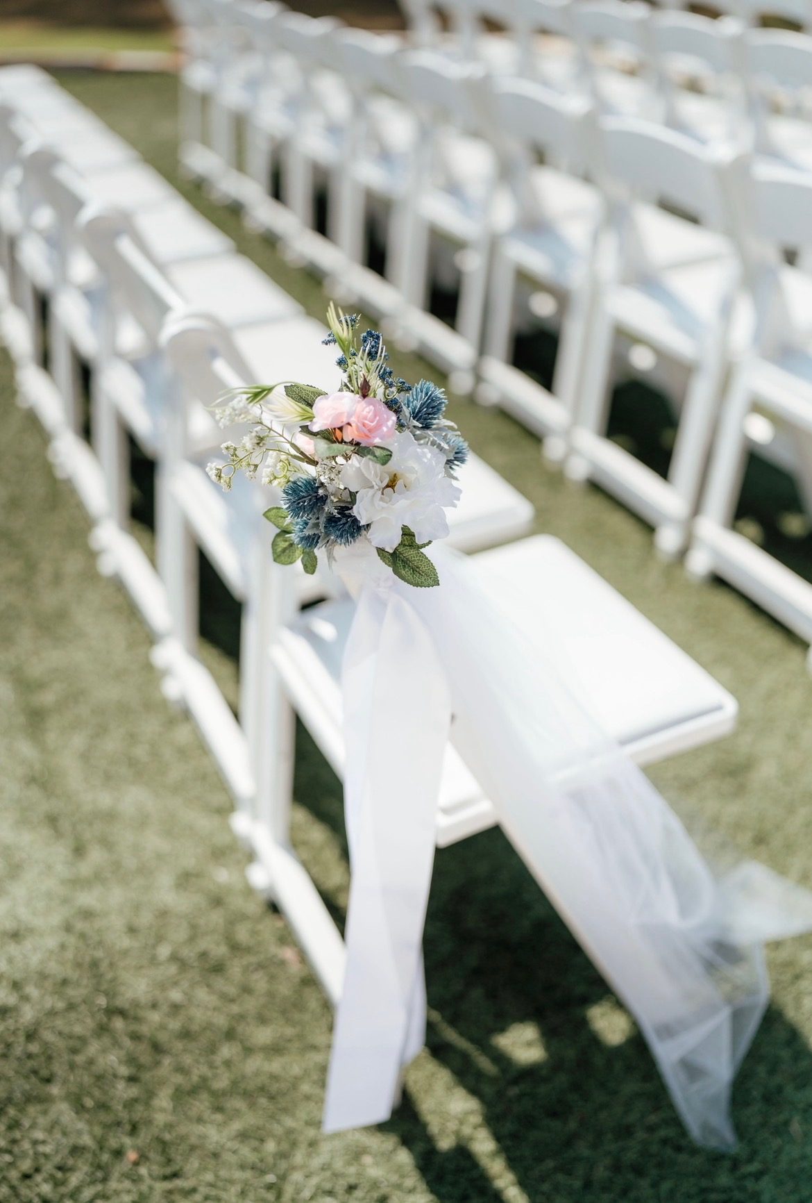 Ceremony aisle chair detail with florals and flowing veil