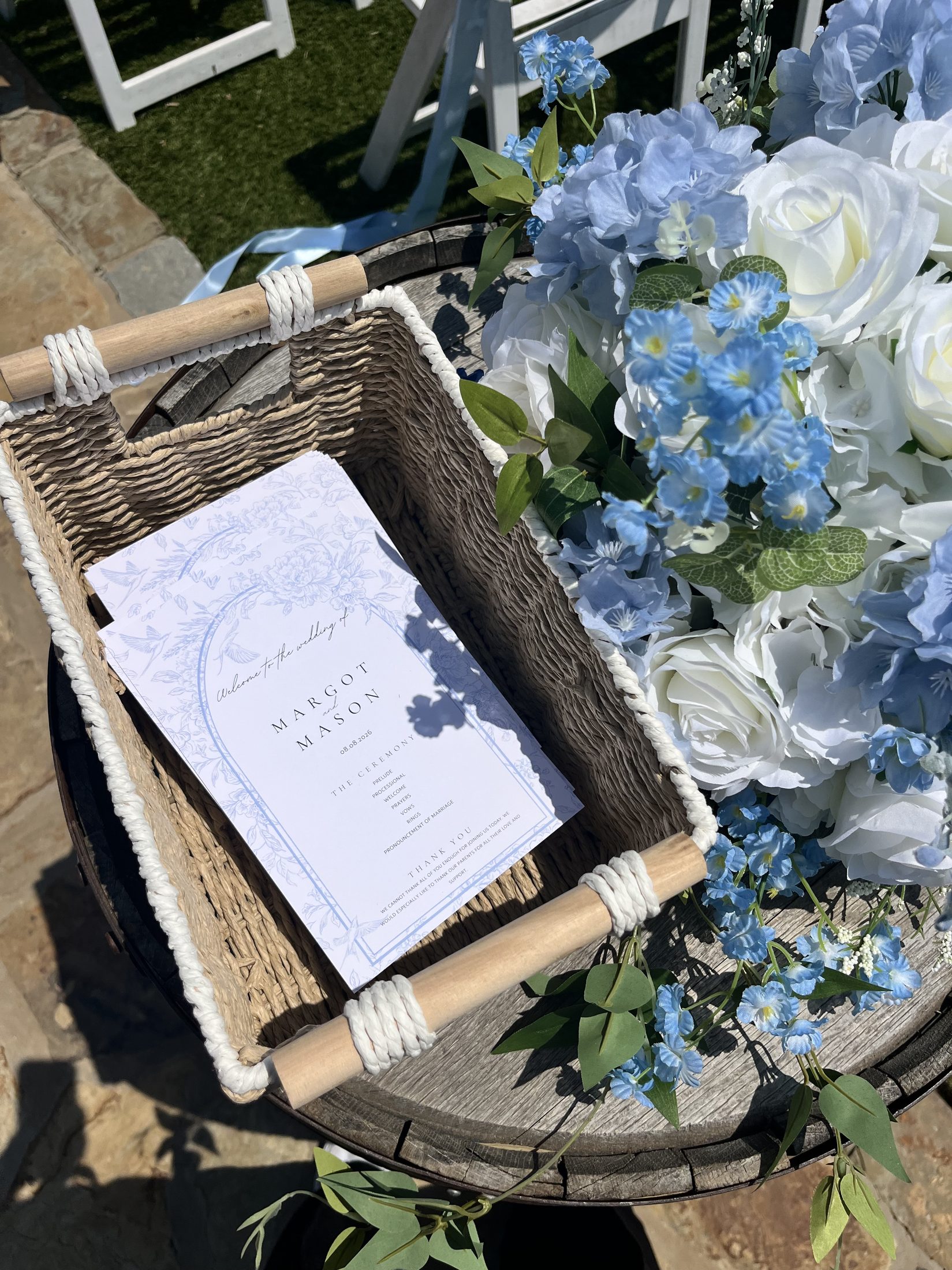 Blue and white floral basket with ceremony program on a barrel table