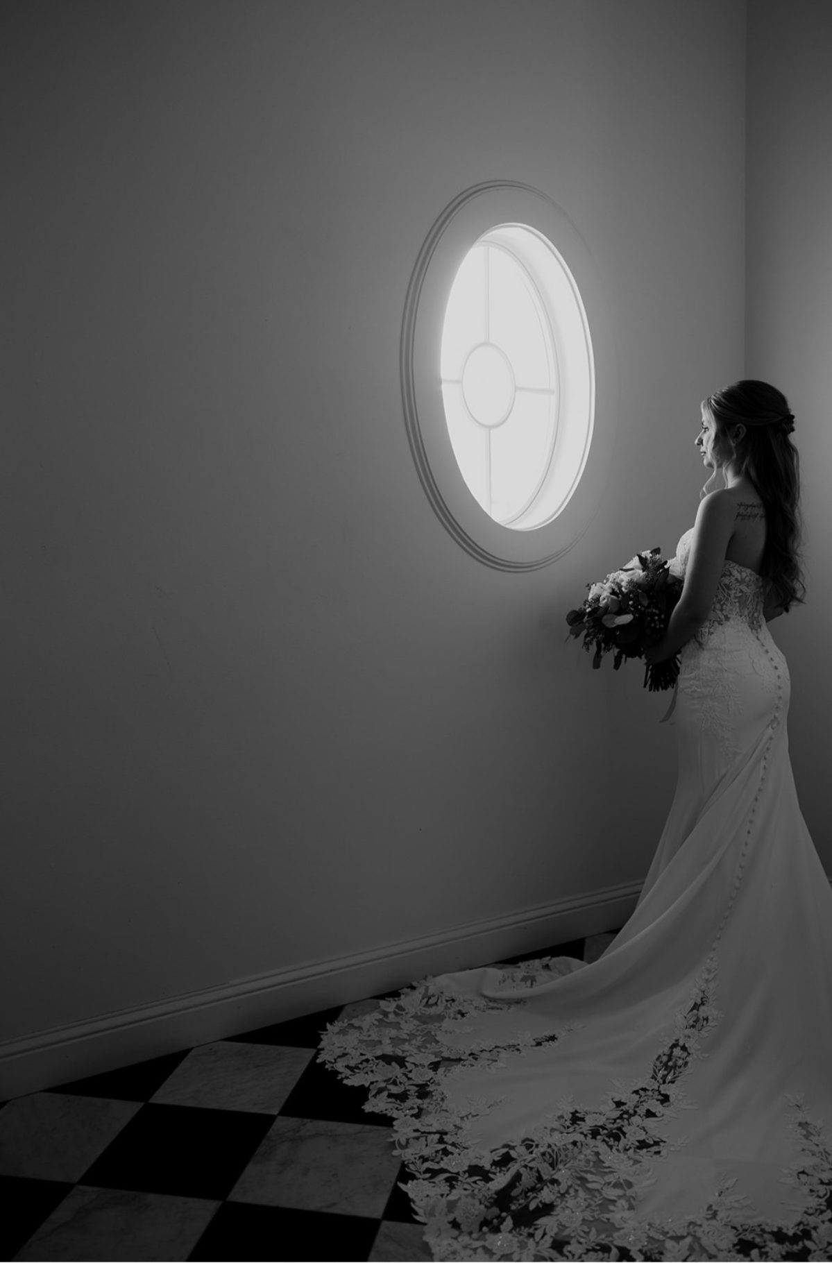 Bride looking out an oval chapel window, black and white