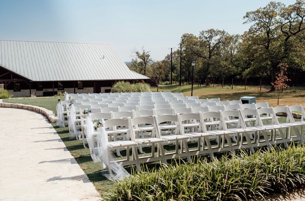 Rows of white ceremony chairs at a Texas hill country venue