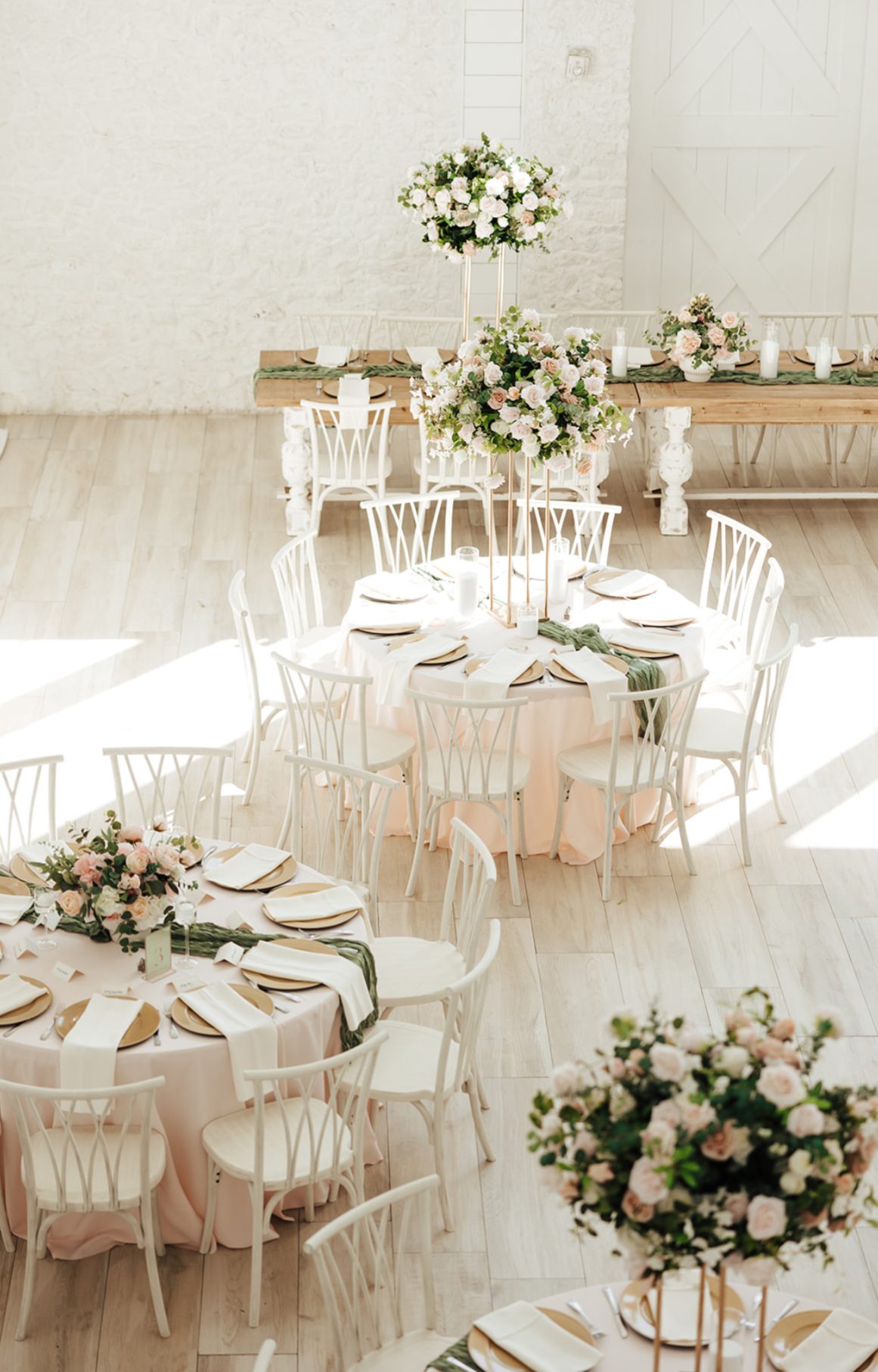 Sunlit reception room set with round tables and florals
