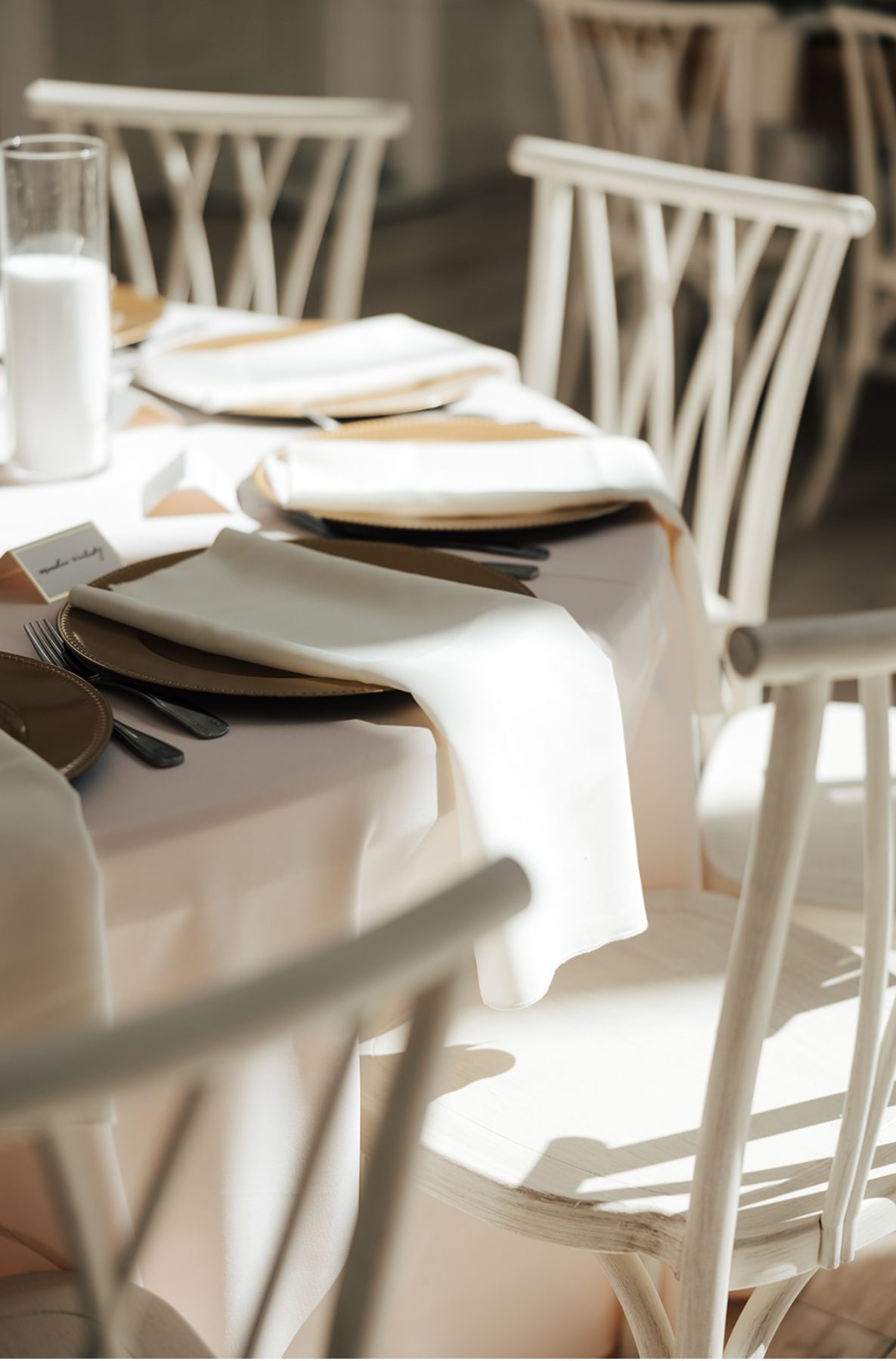 Sunlit table setting with white linens and gold accents