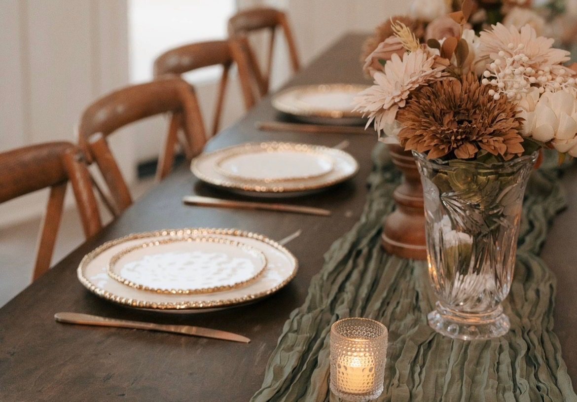 Long wooden table styled with a sage runner and warm florals